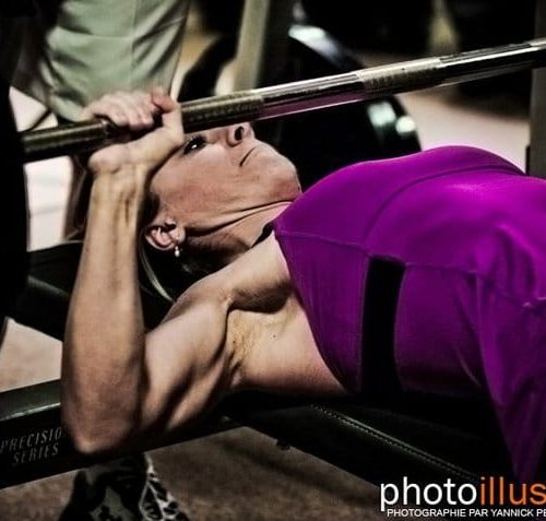 Une femme s'entraîne avec un banc de musculation dans une salle de sport.