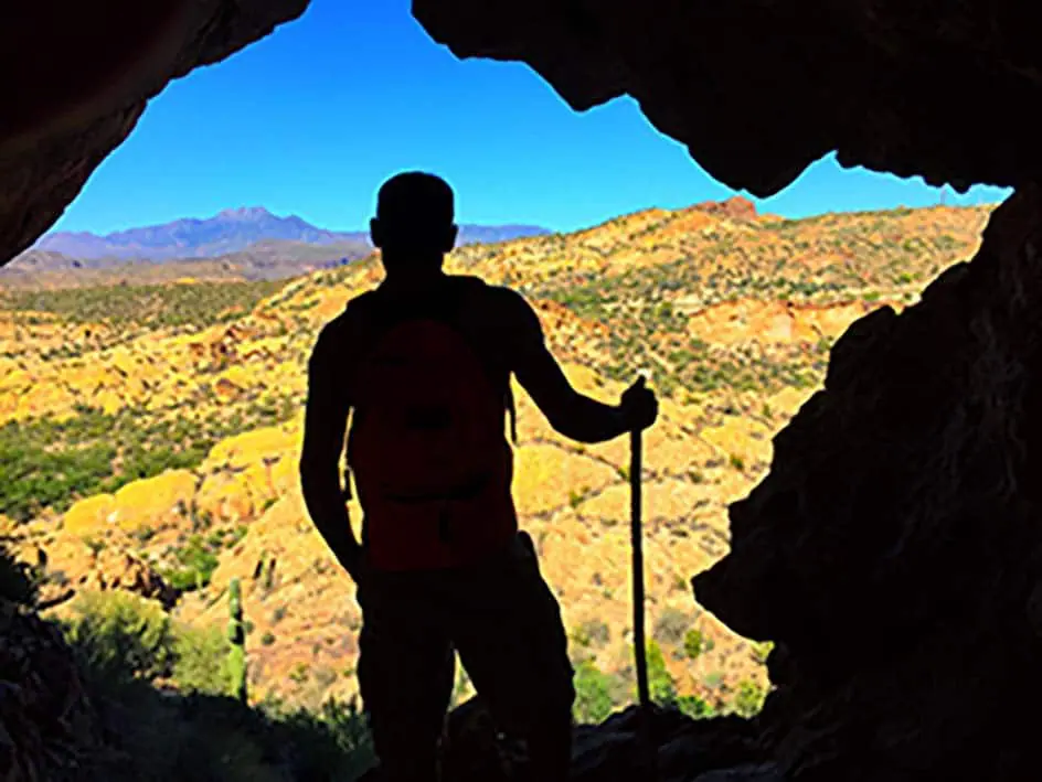 Un homme debout dans une grotte avec un sac à dos.