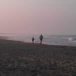 Deux personnes font une promenade sur une plage au crépuscule pour profiter de leurs vacances.