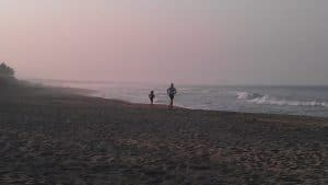 Deux personnes font une promenade sur une plage au crépuscule pour profiter de leurs vacances.