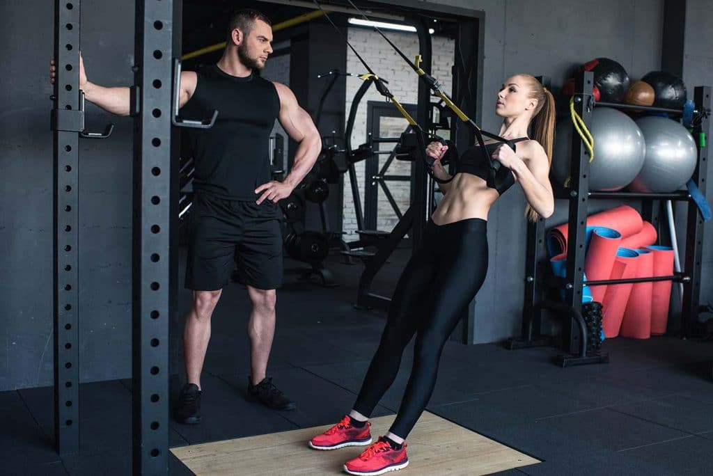 Un homme et une femme faisant des squats dans une salle de sport.