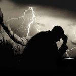 Un homme agenouillé devant un orage, projetant une forte silhouette.
