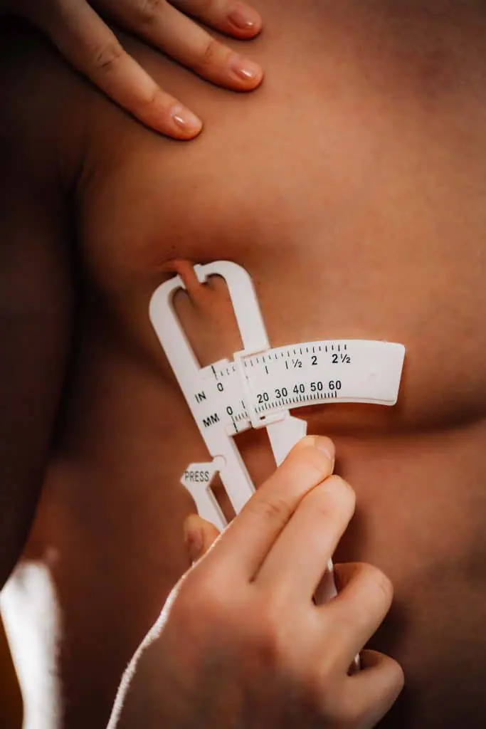 Un homme mesurant sa poitrine avec un ruban à mesurer.