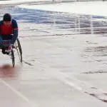 Un homme en fauteuil roulant participant aux Jeux paralympiques sur une piste.