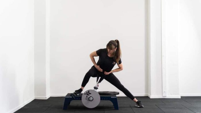 Une femme faisant des squats sur un appareil d'exercice.