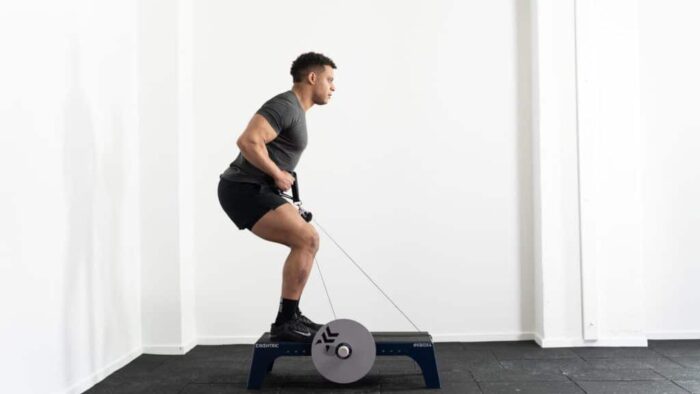 Un homme faisant un squat sur un appareil d'exercice.