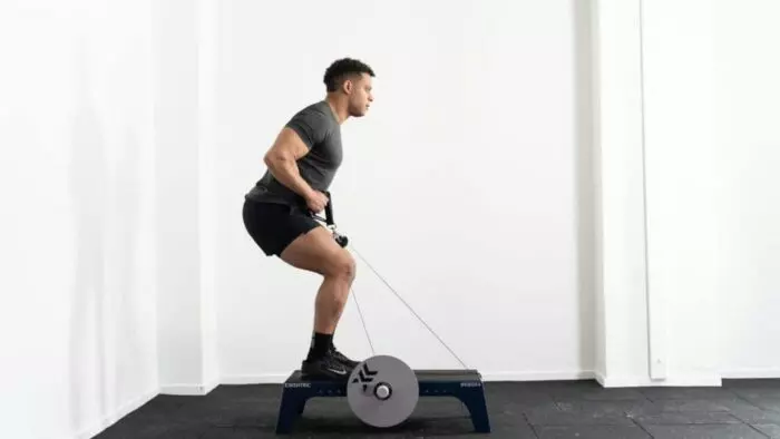Un homme faisant un squat sur un appareil d'exercice.