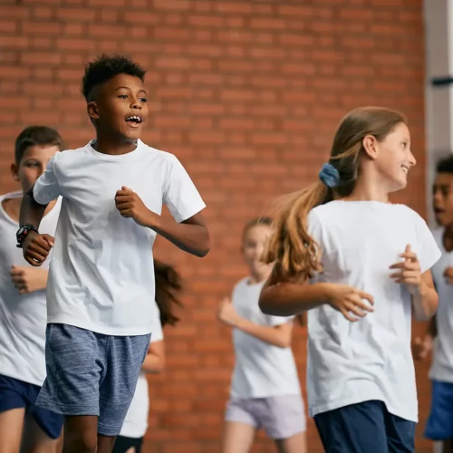 Un groupe d'enfants suivant un cours d'éducation physique dans une salle de sport.